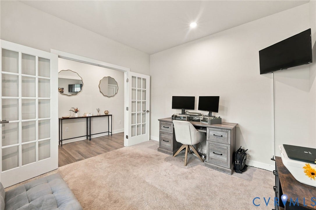 Recessed lighting, light-colored carpeting, and double French doors with grid-patterned glass