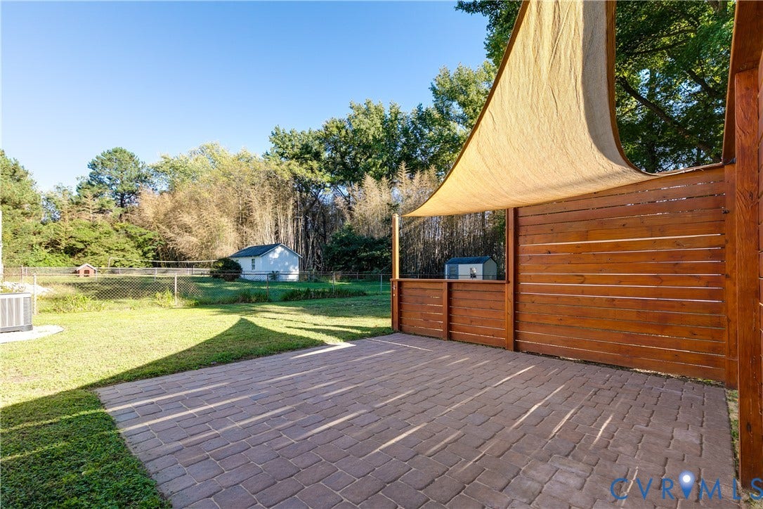 Backyard brick patio with a shade sail creates a comfortable setting for enjoying time outside