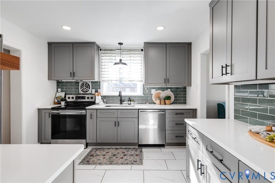 Modern kitchen featuring bright quartz counters, stainless steel appliances, and subway tile backsplash.