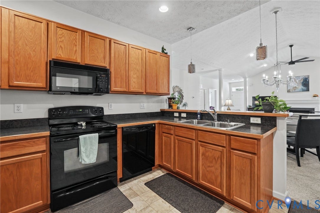251 Pumpkin Place, Harvest Glen, North Chesterfield, VA 23236 Warm wood cabinetry with black appliances and dark countertops define this kitchen, featuring a center island with seating space, stainless steel sink, and pendant lighting