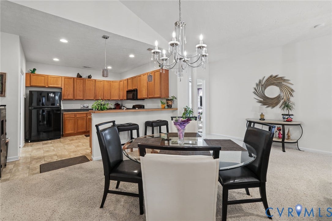 251 Pumpkin Place, Harvest Glen, North Chesterfield, VA 23236 Open-concept living and dining area featuring neutral carpeting, a black glass-top dining table with upholstered chairs, and a crystal chandelier