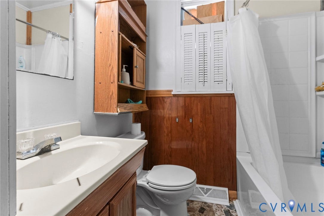 3917 Peyton Avenue, Richmond, VA 23224 White vanity with integrated sink, wall-mounted mirror, and wood-finish cabinetry