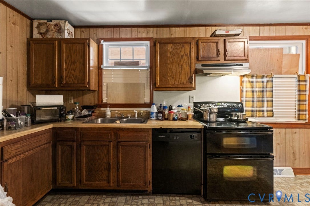 3917 Peyton Avenue, Richmond, VA 23224 Wood-paneled walls, wood-finish cabinetry, stainless steel sink, black dishwasher, and black double oven
