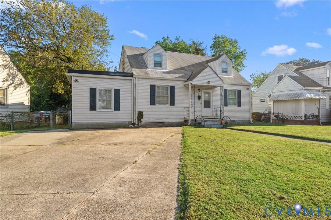 3917 Peyton Avenue, Richmond, VA 23224 White siding exterior with a pitched roof, dormer windows, and a paved driveway