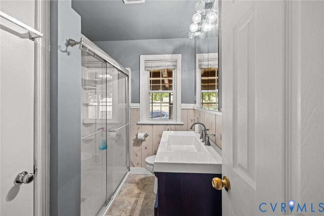 2405 Dumbarton Road, Henrico, VA 23228 Bathroom featuring a glass-enclosed shower, dual-sink vanity, and textured wall paneling