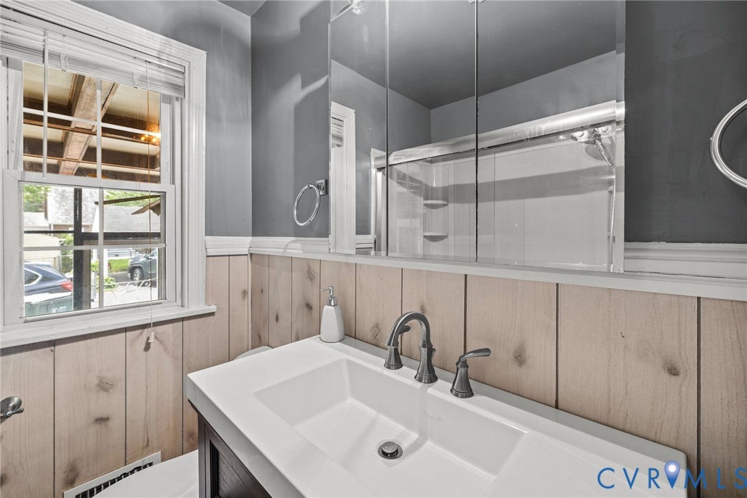 2405 Dumbarton Road, Henrico, VA 23228 White single-hung window with blinds, wood paneling, white vanity with integrated sink, dual-handle faucet, and mirrored medicine cabinet