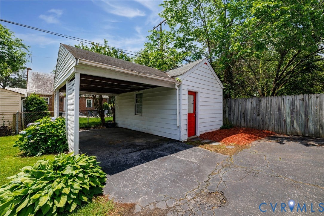 2405 Dumbarton Road, Henrico, VA 23228 Carport with white siding, exterior storage shed with red door, wood privacy fence, and paved surface