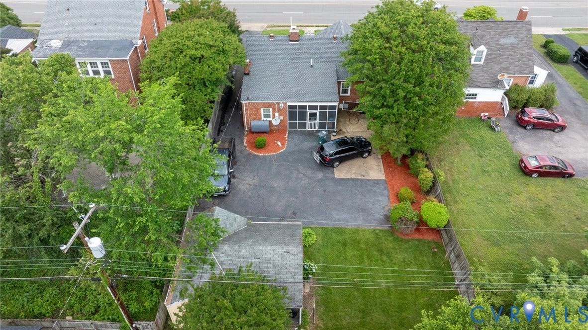 2405 Dumbarton Road, Henrico, VA 23228 Aerial view showcasing a brick ranch-style residence situated on a generous lot with mature shade trees, asphalt driveway, and expansive lawn space