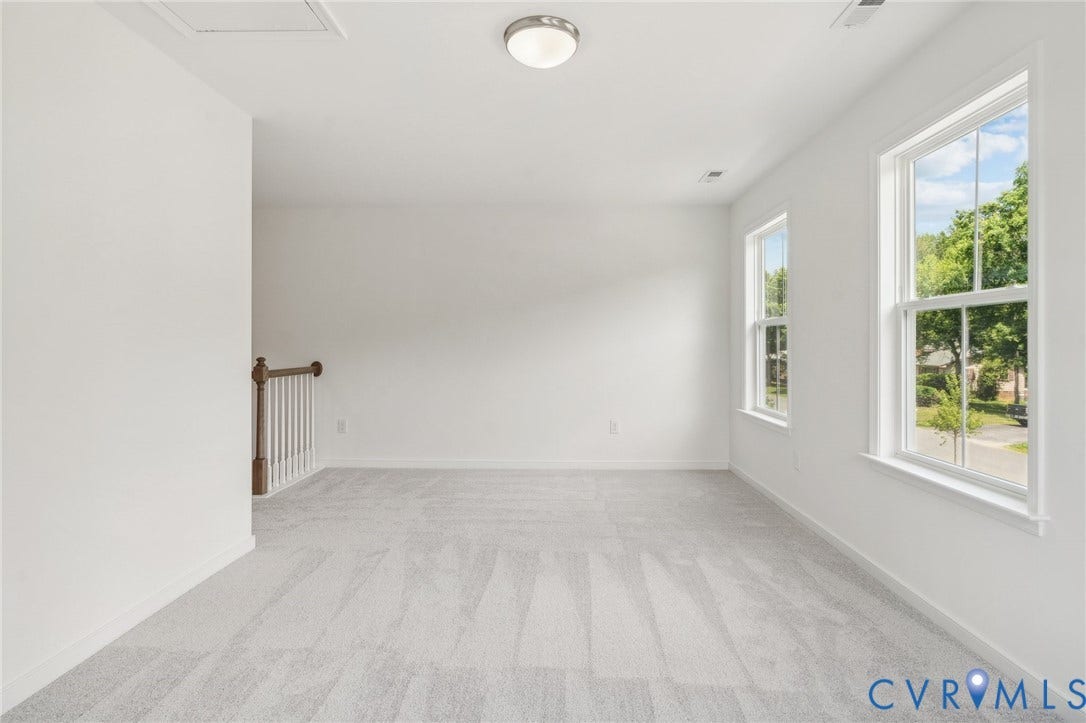 9116 TERROIR Lane, Viniterra Villas, New Kent, VA 23124 Spacious room featuring light gray carpeting, crisp white walls, multiple windows with white trim, and a semi-flush mount ceiling light
