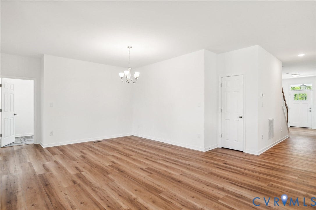 9116 TERROIR Lane, Viniterra Villas, New Kent, VA 23124 Expansive open-concept room featuring wood-finish flooring, white painted walls, and a chandelier lighting fixture