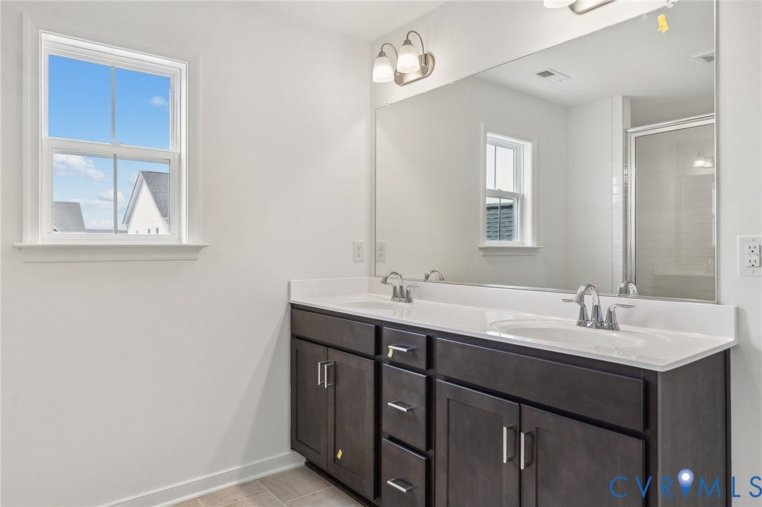9116 TERROIR Lane, Viniterra Villas, New Kent, VA 23124 Dual vanity with white countertops, dark wood-finish cabinetry, and brushed nickel fixtures
