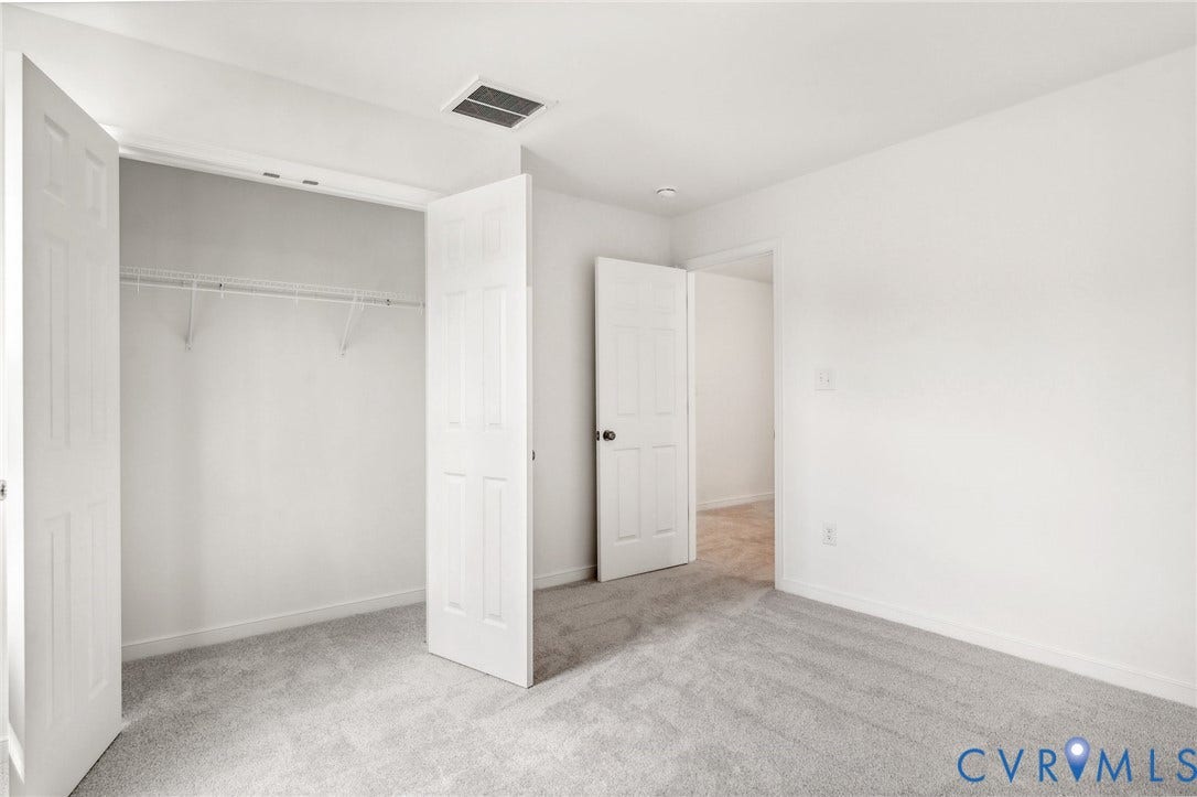 9116 TERROIR Lane, Viniterra Villas, New Kent, VA 23124 Light gray carpeting throughout, white walls, and a white bi-fold closet door