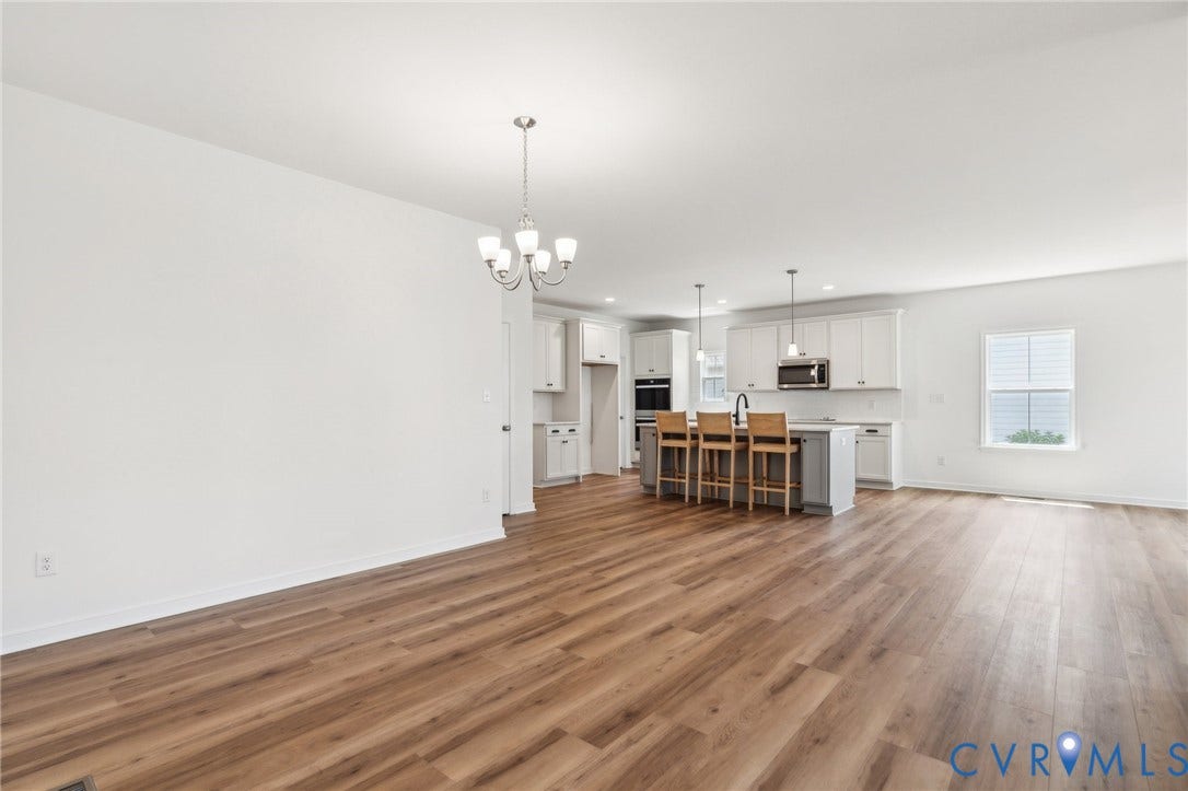 9116 TERROIR Lane, Viniterra Villas, New Kent, VA 23124 Open-concept living area featuring wood-finish flooring, a contemporary chandelier, recessed lighting, and a kitchen island with pendant lighting and built-in appliances