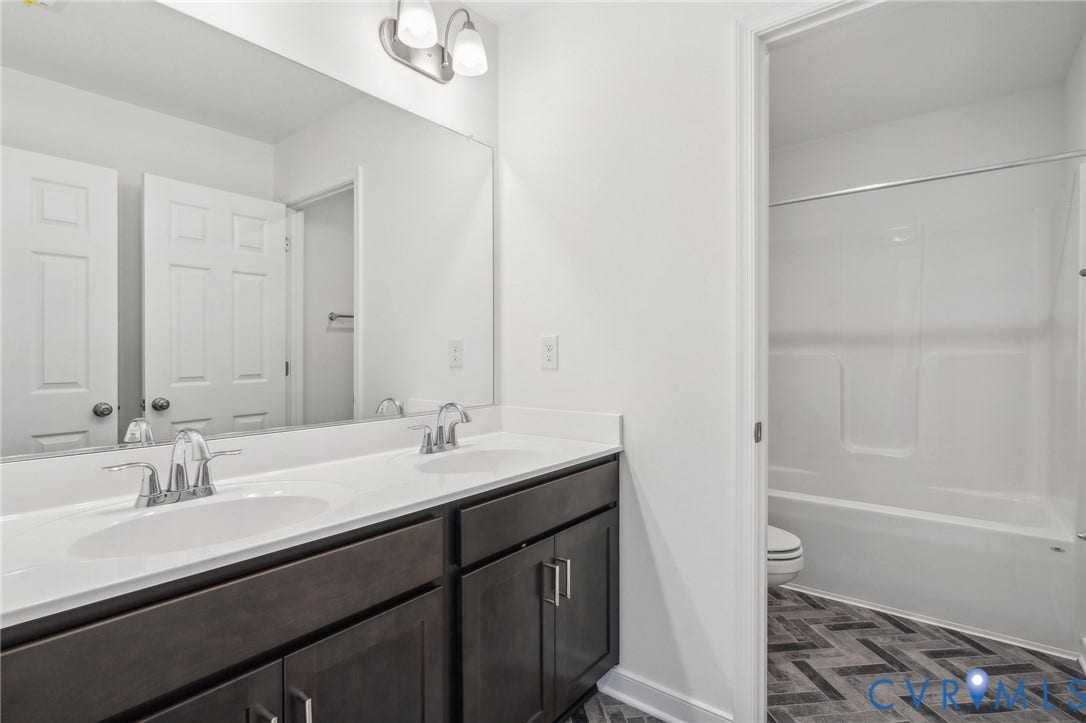 9116 TERROIR Lane, Viniterra Villas, New Kent, VA 23124 Dual vanity with dark wood-finish cabinetry, white countertop, and chrome fixtures