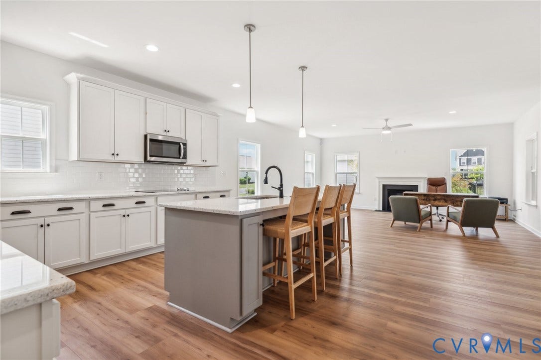 9116 TERROIR Lane, Viniterra Villas, New Kent, VA 23124 Spacious kitchen featuring an island with seating, white cabinetry, a tiled backsplash, and stainless steel appliances