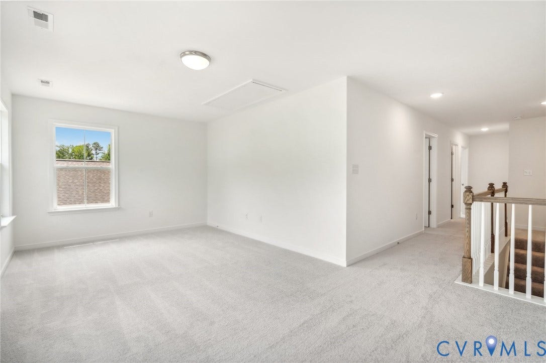 9116 TERROIR Lane, Viniterra Villas, New Kent, VA 23124 Carpeted room with a single window, a flush-mount ceiling light, and access to a hallway with a wood and white banister