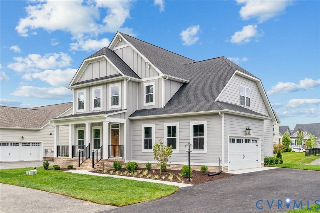 9116 TERROIR Lane, Viniterra Villas, New Kent, VA 23124 Two-story residence featuring light gray siding, white trim, a covered front porch, an attached garage, and an asphalt driveway