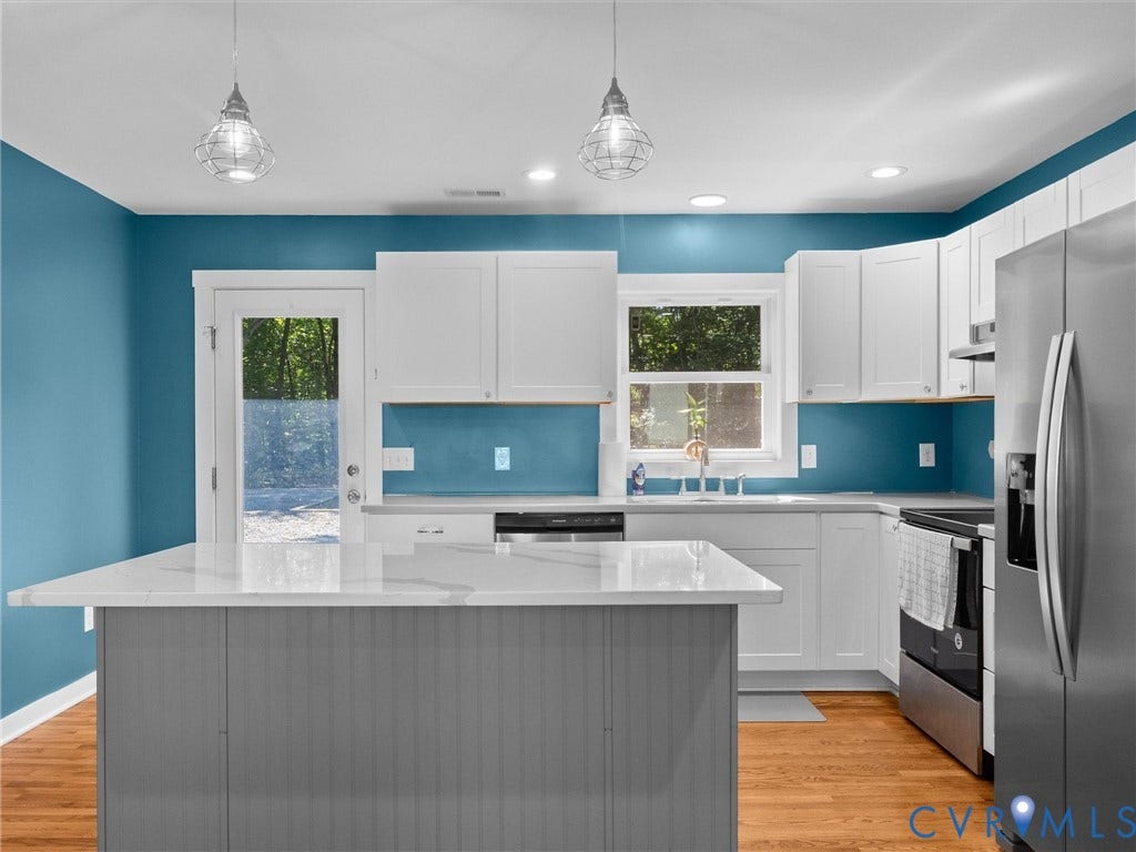 Kitchen with white cabinetry, stainless steel appliances, wood-finish flooring, a central island with a light-toned countertop, and recessed lighting
