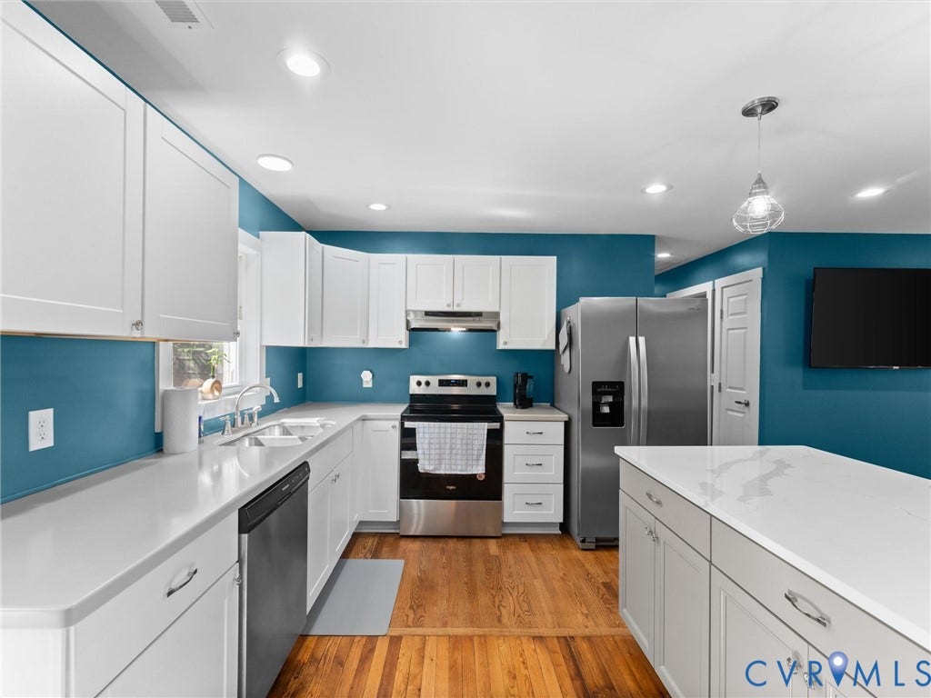 White cabinetry, solid surface countertops, stainless steel appliances, wood-finish flooring, and recessed lighting