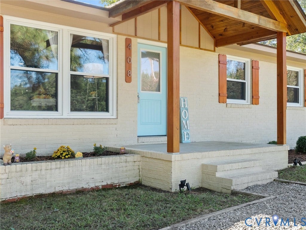 Brick exterior with a covered entry, light blue door, and white frame windows
