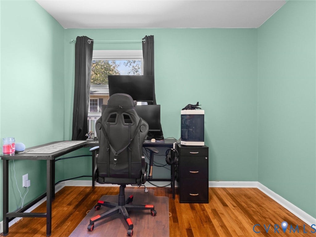Hardwood flooring, light-colored walls, window with dark drapes, white trim