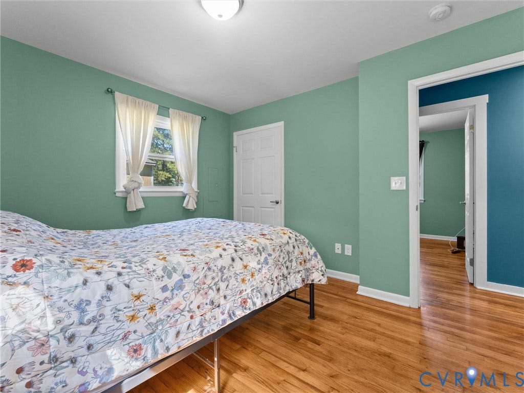 Hardwood flooring, painted walls, white trim, window with natural light, and a flush mount ceiling light fixture