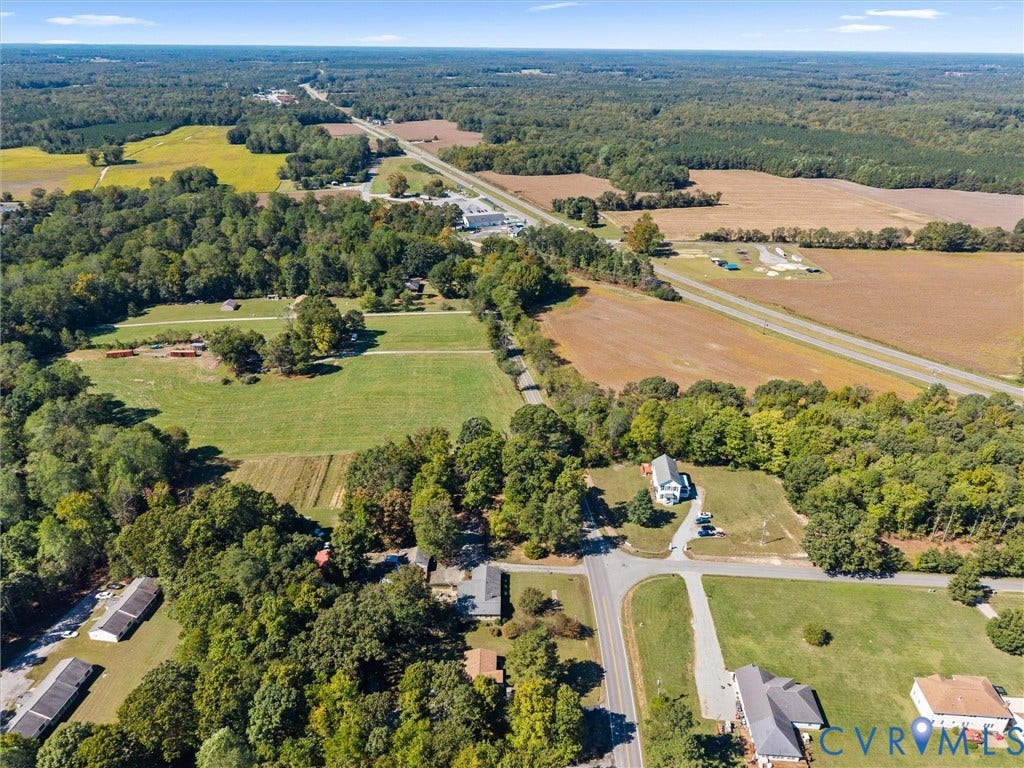 Expansive land with a mix of wooded and open fields, featuring a prominent roadway, and a clear sky overhead