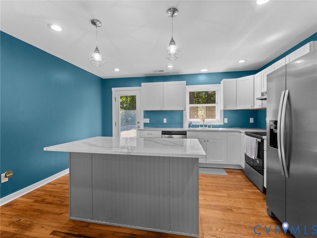 Kitchen featuring wood-finish flooring, recessed lighting, a central island with a light-toned countertop, white cabinetry, and stainless steel appliances