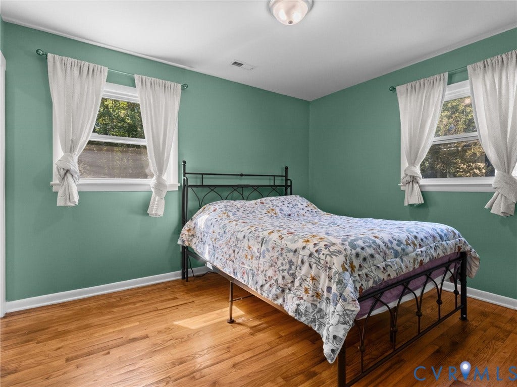 Wood-finish flooring, two windows with white trim, and a ceiling-mounted light fixture