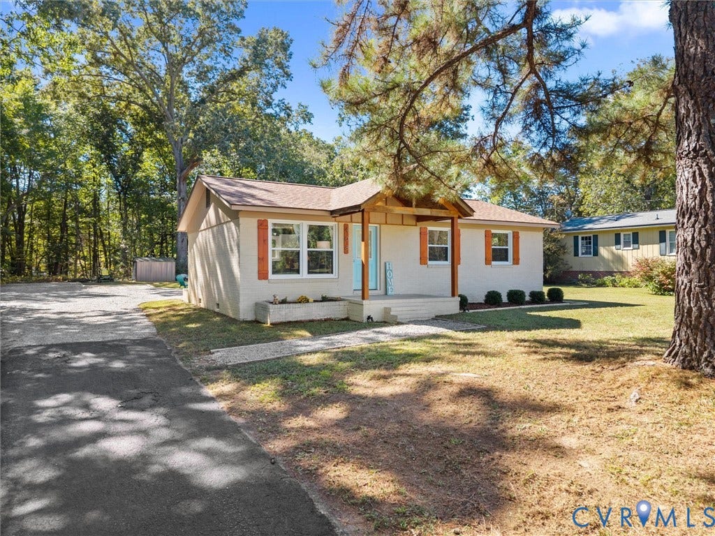 Single-story residence featuring a covered front porch, light-colored exterior siding, and a paved driveway