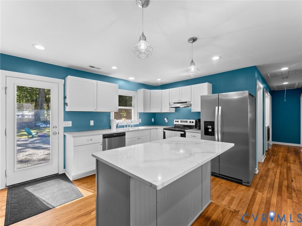 Kitchen featuring an island with a light-toned countertop, stainless steel appliances, recessed lighting, and wood-finish flooring