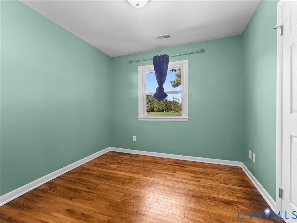 Wood-finish flooring with white trim and a single window