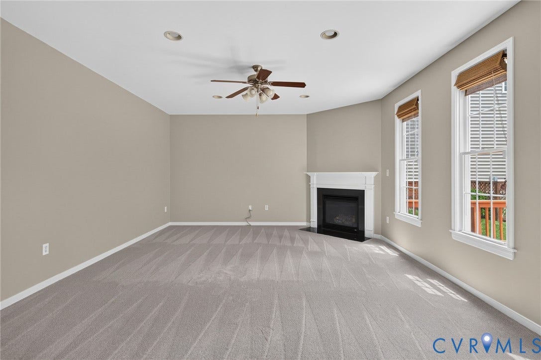 Recessed lighting, ceiling fan, fireplace with white mantel, and two windows with blinds