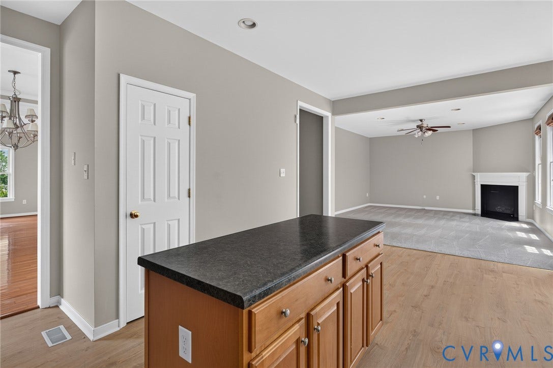 Kitchen island with wood cabinetry and dark countertop