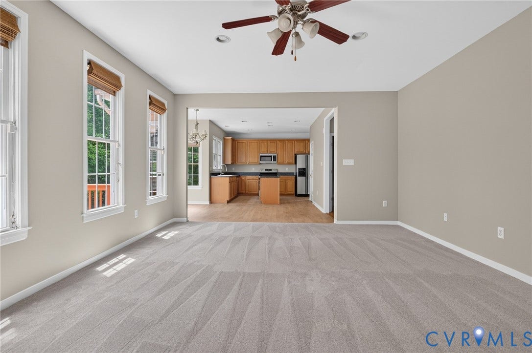 Spacious room with light gray carpeting, neutral wall paint, and a ceiling fan