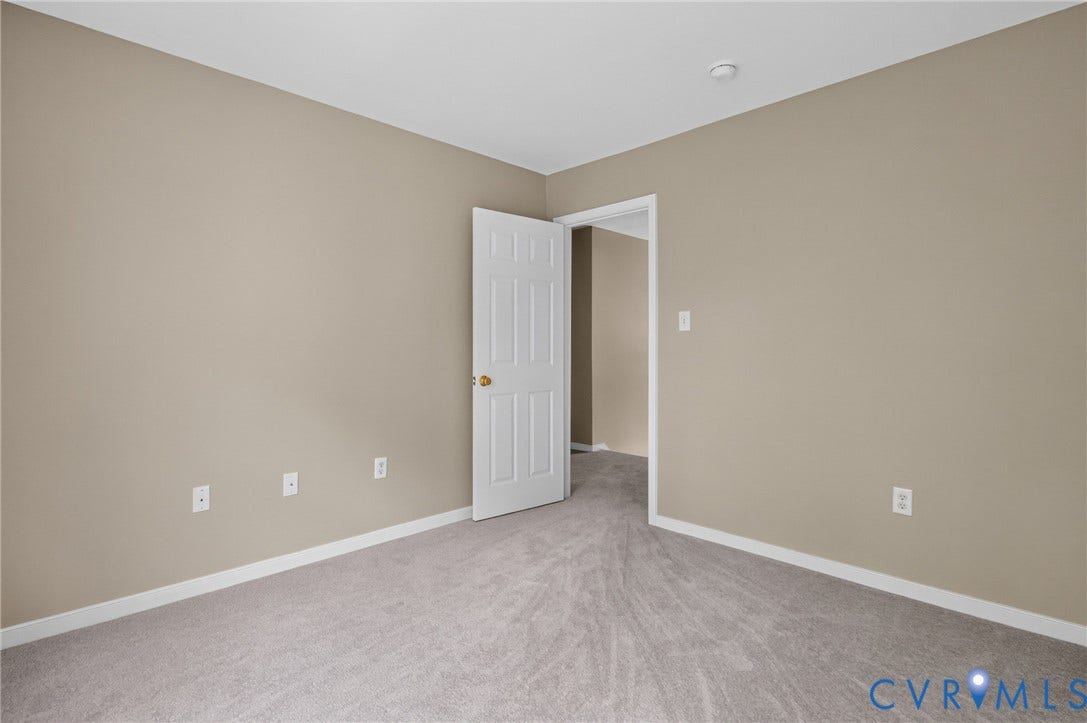 Neutral wall paint, white trim, light gray carpeting, and a white interior door