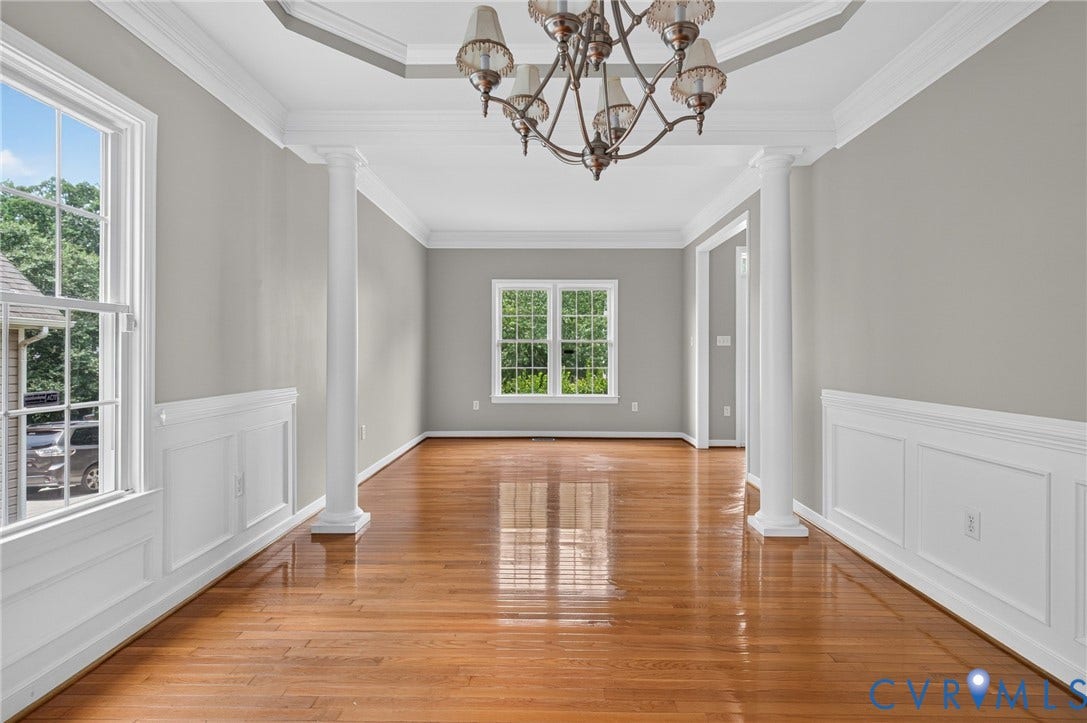 Hardwood flooring throughout, tray ceiling, wainscoting, crown molding, and columns