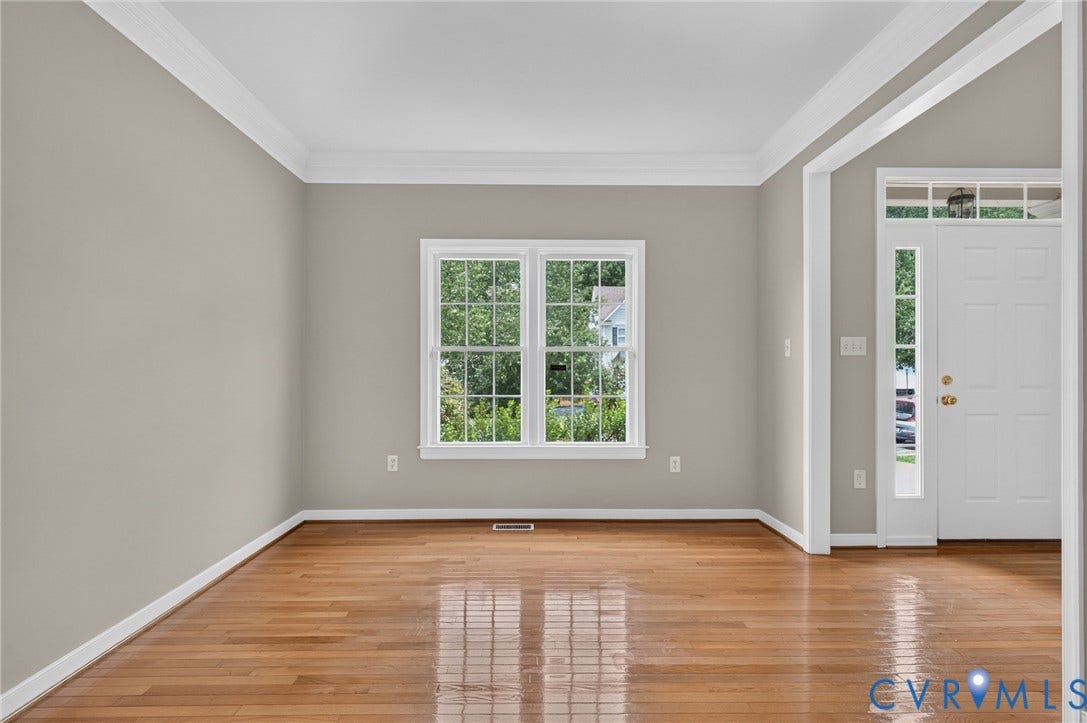 Hardwood flooring, crown molding, white trim, recessed window, and transom window entryway