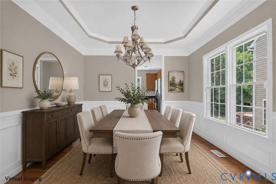 Tray ceiling with crown molding, wood-finish flooring, white paneled wainscoting, and large windows with grilles
