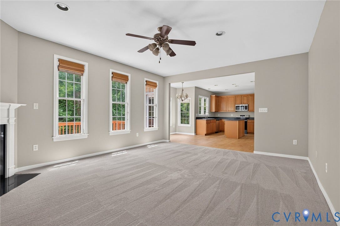Recessed lighting, ceiling fan, fireplace with mantel, multiple windows with blinds, and wood-finish flooring in the kitchen