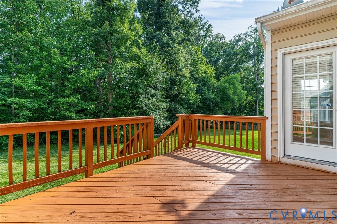 Expansive wood deck with railing and stairs, featuring a glass-paneled exterior door and siding