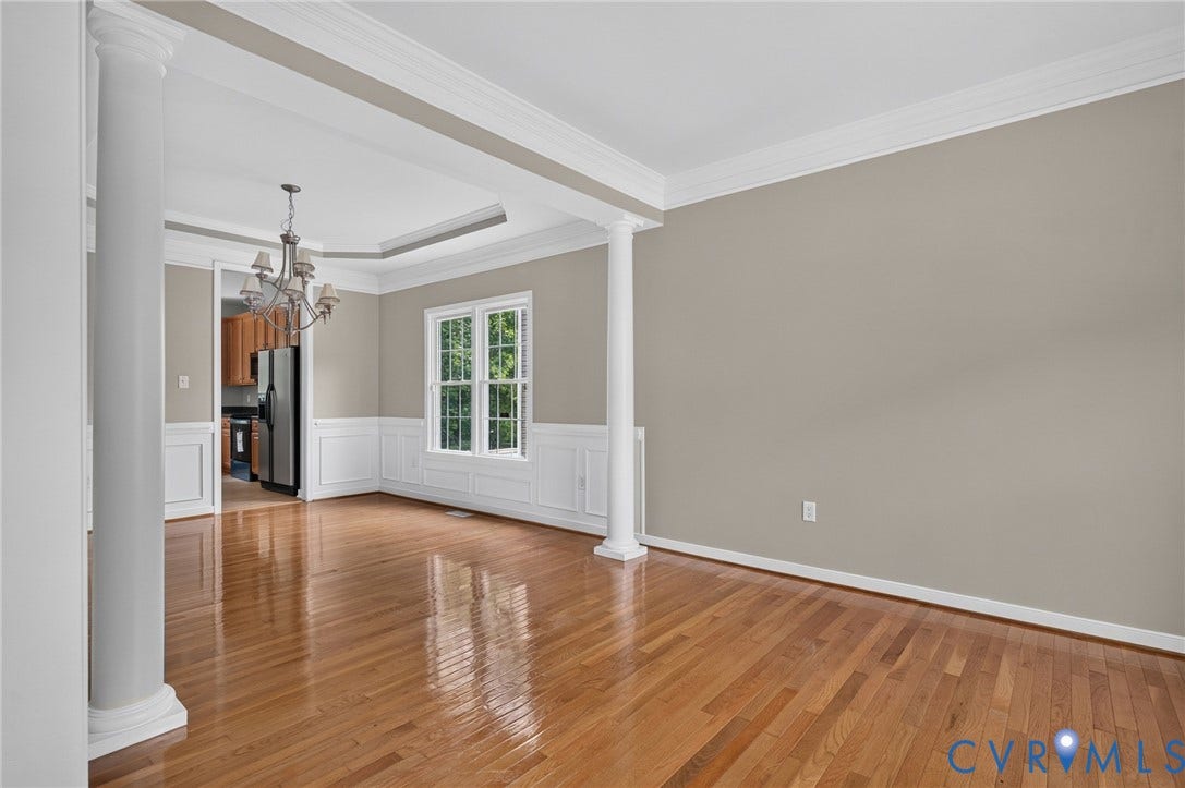 Hardwood flooring throughout, featuring decorative columns, crown molding, and wainscoting