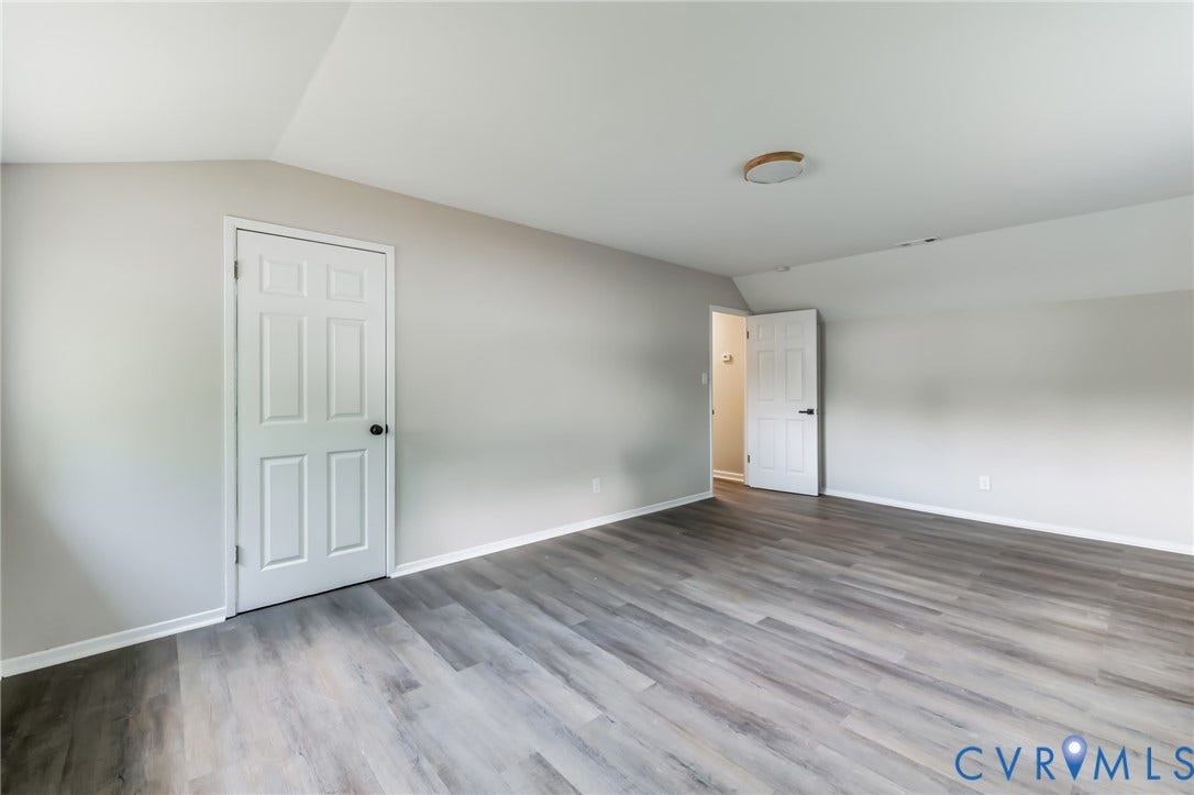 Wood-finish flooring, neutral wall tones, white trim, and a flush-mount ceiling fixture