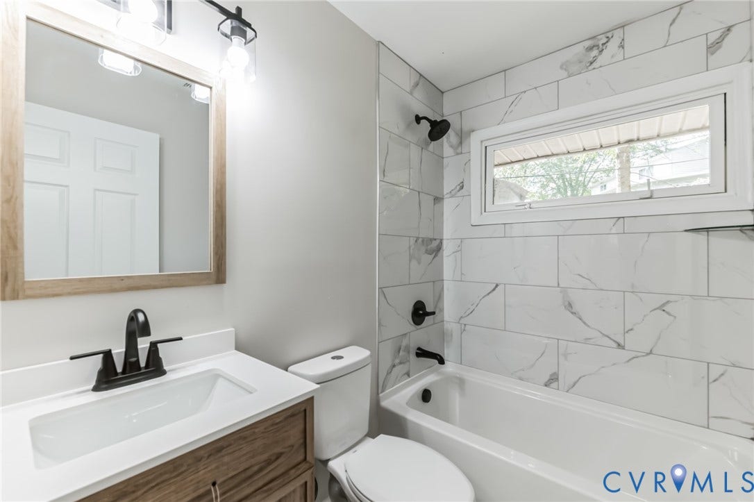 Bathroom featuring a wood-finish vanity with a white countertop, undermount sink, and matte black faucet