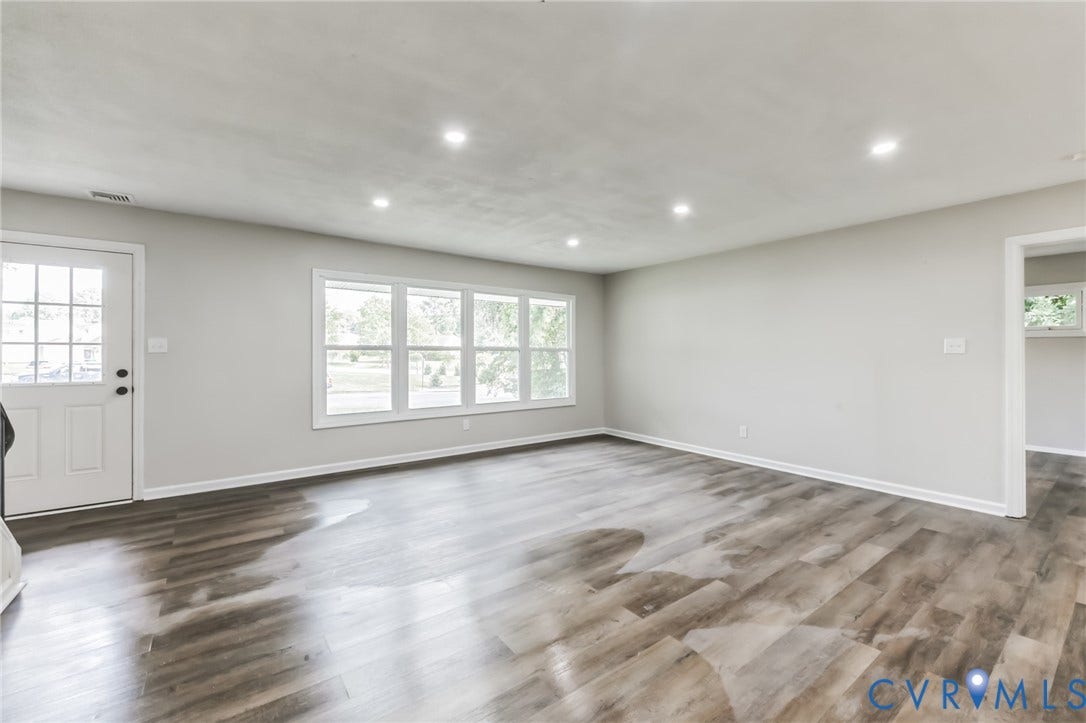 Wood-finish flooring with white baseboards, recessed ceiling lighting, light gray painted walls, and a multi-pane window assembly