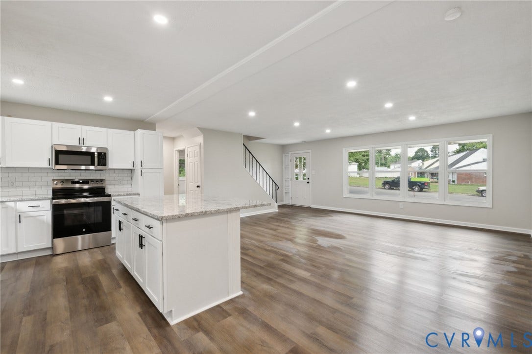 Contemporary kitchen featuring white cabinetry, stainless steel appliances, a center island with countertop, and wood-finish flooring
