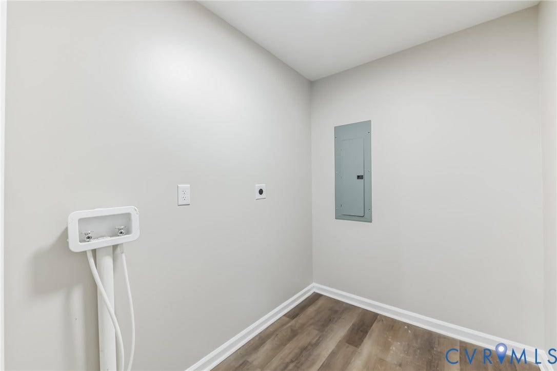 Utility area featuring wood-finish flooring, white walls, and an electrical panel