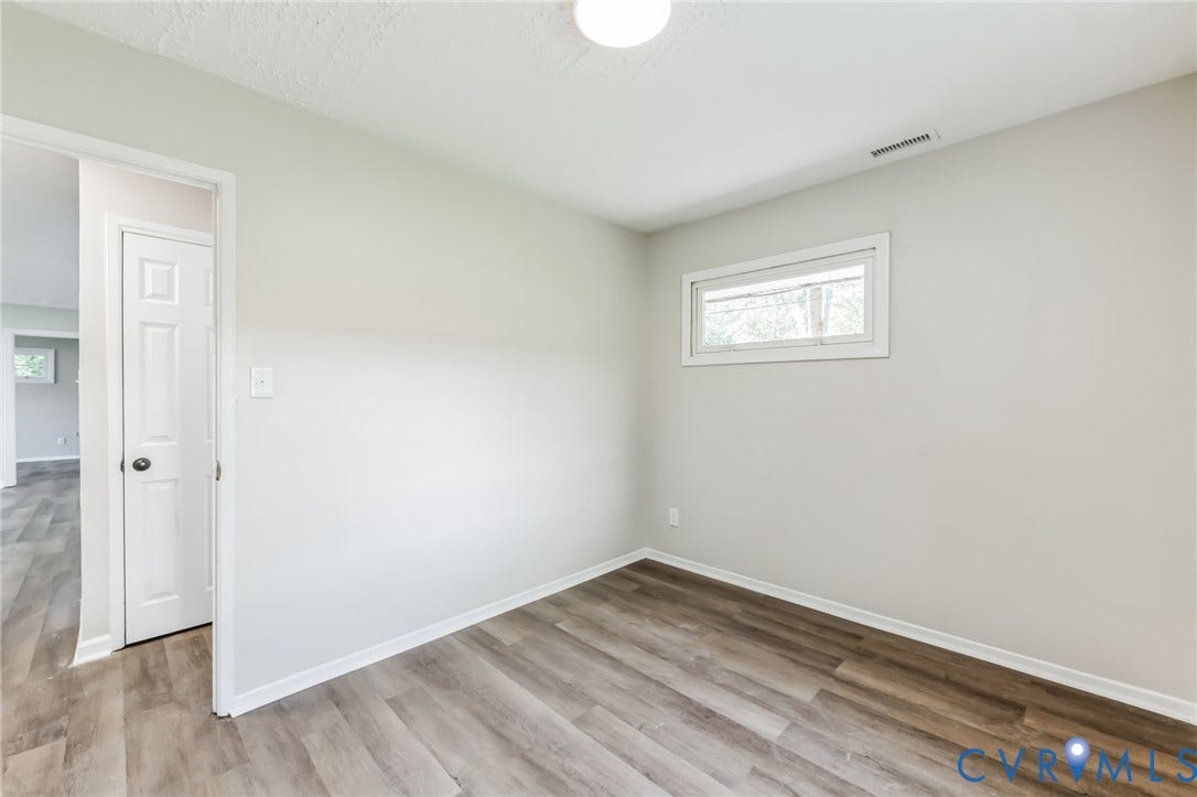 Wood-finish flooring, white walls, and a single window with white trim