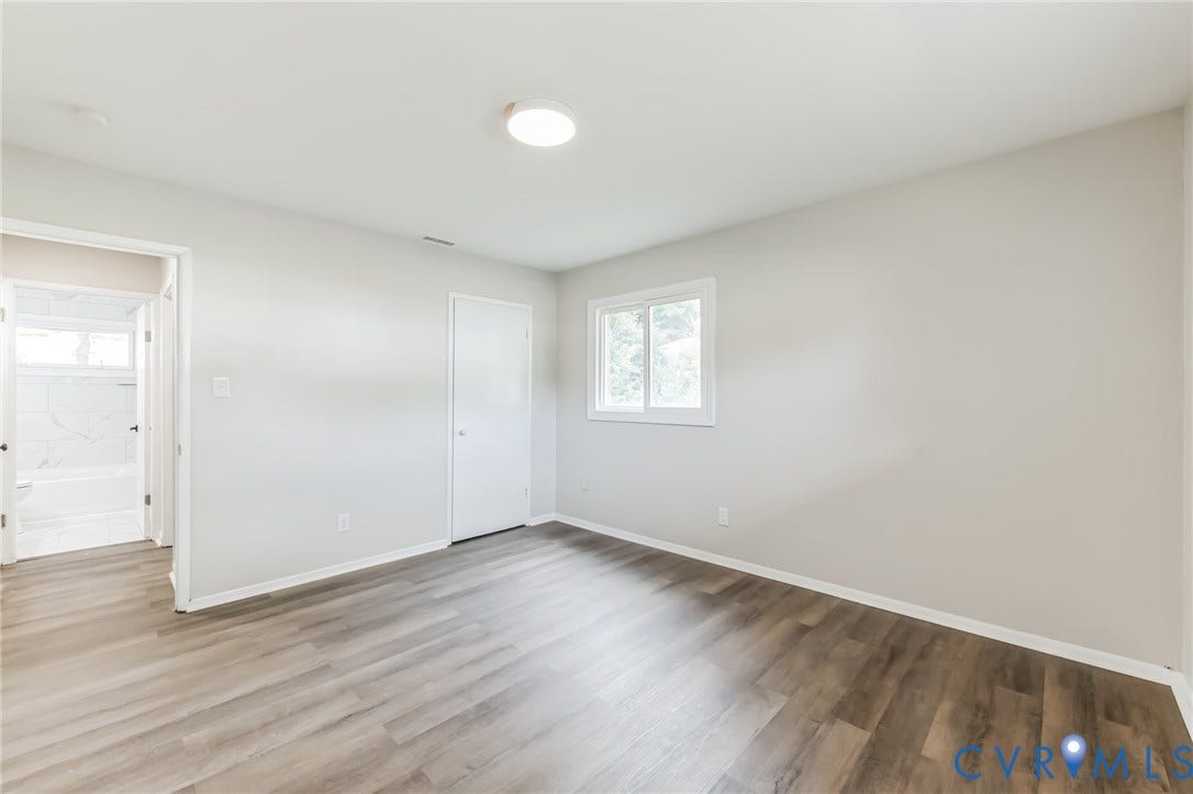 Wood-finish flooring, white walls, and a window providing natural illumination