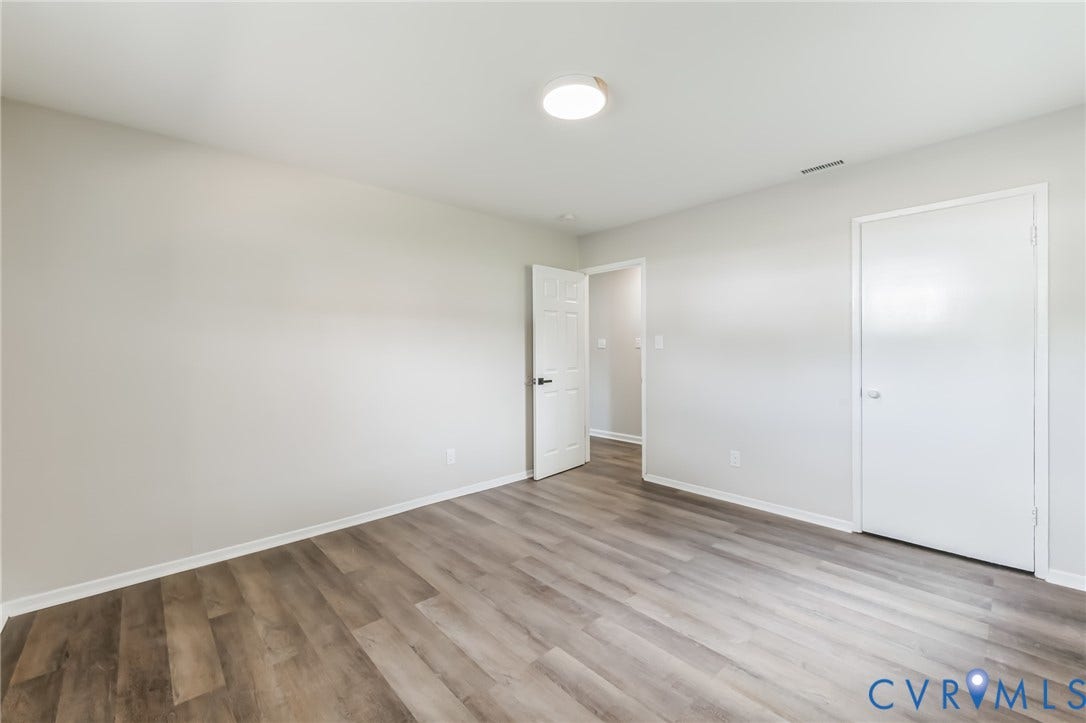 Wood-finish flooring, white trim, recessed lighting, and a white interior door